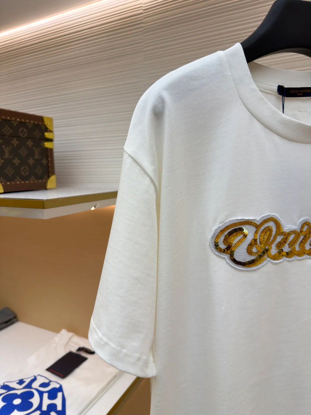 LOUIS VUITTON cotton round neck embroidered Vuitton signature logo short sleeves ●Original version: purchased and developed for 12300 ●Item number: 1682272-A10 ●Fabric: cotton fabric ●Technology: embroidery production ●Color: white ●Version: fitted version ●Weight: about 270 grams ●Size: S-M-L-XL ●Description: This white short-sleeved T-shirt is made of high-count combed cotton fabric and has been treated with pre-washing technology. It has a soft and skin-friendly touch and is not easy to deform. The silhouette of the shirt is a loose shoulder design, which meets the needs of modern casual wear. The core decoration area on the chest uses hand-beading and bronzing technology, and uses metallic gold sequins and embroidery threads intertwined to outline a three-dimensional letter pattern. The sequins are layered and inlaid, and each one is manually positioned and fixed by craftsmen to ensure a regular texture and uniform gloss. The edges of the letters are sewn with matte silk thread to form a visual contrast between gold and matte, while reinforcing the decorative structure to avoid falling off during wear. The neckline uses double-needle hemming technology and is matched with ribbed cuffs of the same fabric. It is durable and fits the neck. The overall craftsmanship combines handicraftsmanship with modern clothing technology, and the details show exquisite texture. The overall wiring is straight and delicate, the fabric is comfortable and soft, and the color is consistent without color difference. It can be matched with the same style to create a fashionable look and control various occasions. Customized accessories, complete with three standards, same style for men and women!